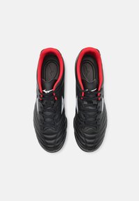 Scarpe da calcio nere con accenti rossi, in materiale sintetico, superficie texturizzata e logo bianco. Presentano un sistema di allacciatura standard.