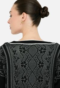Maglione nero con un motivo testurizzato e dettagli argentati, una striscia colletto bianca e una vestibilità aderente con una finitura liscia.