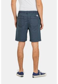 Shorts de mezclilla azul marino con un corte relajado, que presentan dos bolsillos traseros y una cinturilla, combinados con zapatillas azules.