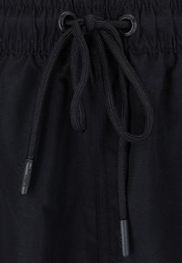 Schwarzer Kordelzug mit einem strukturierten, elastischen Taillenbundmaterial. Der Kordelzug ist fest gewebt und verfügt über plastische Spitzen für einen sicheren Verschluss.