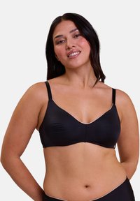 Soutien-gorge noir sans coutures avec une texture lisse, doté de bretelles réglables et d'une finition en contraste de couleur claire le long de l'encolure.