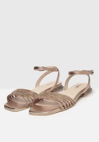 Goldene und bronzefarbene flache Sandalen mit mehreren mit Perlen besetzten Riemen, offenen Zehen und Knöchelriemen. Glatte Textur und viereckiger Zehenbereich.