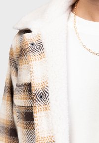 Fleecejacke mit einem gemusterten äußeren Design in Creme, Braun und Orange, einem weichen, strukturierten Innenfutter und silbernen Hardware-Akzenten.