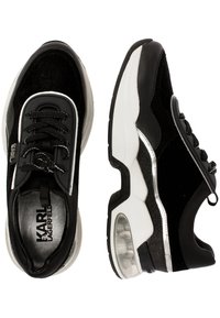 Baskets noires composées d'un mélange de daim et de matériaux synthétiques, avec un design à lacets, des accents argentés et une semelle transparente amortissante à coussin d'air.