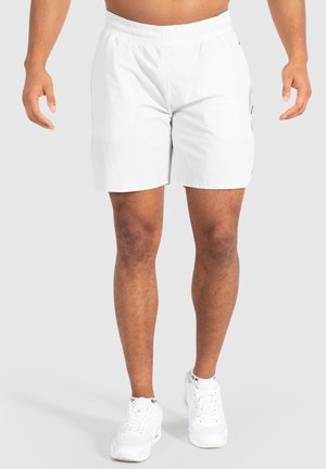 Weiße Shorts aus leichtem Stoff, mit einem elastischen Bund und einem schlichten Design mit Seitentaschen. Getragen mit weißen Sneakers.