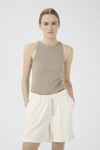 Beige ribbet tanktopp med rund hals og logo detaljer; kombinert med kremfargede shorts med snøring og sidelommer. Glatt tekstur, uformell design.