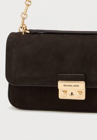 Czarna zamszowa torebka na ramię z złotymi akcentami, z zapięciem na zamek i odpinanym łańcuszkiem. Teksturowana powierzchnia.