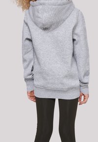 Sudadera con capucha de color gris claro, con una tela texturizada, puños y dobladillo elásticos, que presenta un gran yugo trasero y un corte relajado. Combinada con leggings negros.