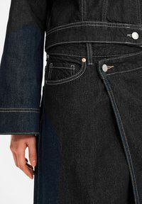 Denim jas met een mix van donkerblauwe en zwarte tinten, met brede mouwen, zichtbare stiksels en metalen knopen bij de taille en zakken.