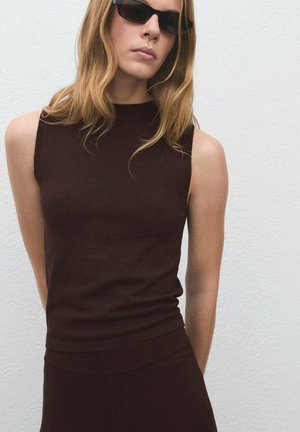 Débardeur en tricot marron sans manches avec col montant, coupe slim et ourlet côtelé. Texture lisse et design minimaliste, associé à des lunettes de soleil noires.