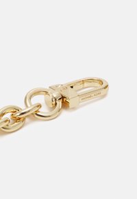Fermoir en métal doré avec une boucle arrondie, un design en barre et des détails gravés avec "Michael Kors" sur le côté. Fini lisse et brillant.