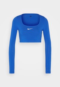 Blå långärmad crop top i stretchy tyg. Har en rund halsringning och en vit Nike-logotyp på bröstet.