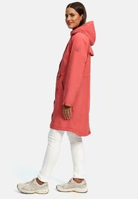 Raspberry-colored long coat with a hood, drawstring waist, side pockets, and buttoned cuffs, paired with white pants and light sneakers.