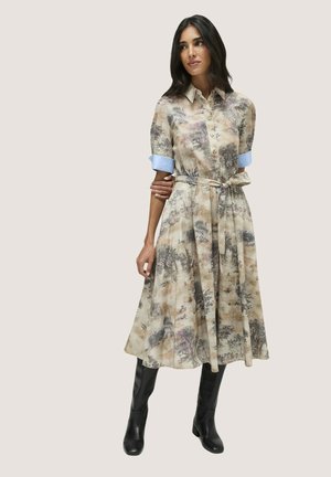 Blumenmuster Hemdkleid in Beige, mit durchgehender Knopfleiste, kurzen ärmeln mit blauen Bündchen und einem passenden Gürtel. Tragen mit knielangen schwarzen Stiefeln.