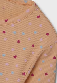 Das gerippte Pfirsichgewebe weist ein Muster aus kleinen Herzen in Pink, Hellblau und Burgunderrot auf. Der Ausschnitt hat einen einfachen runden Stil.