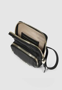 Borsa nera con cerniera e dettagli in metallo dorato, caratterizzata da un esterno in pelle liscia, accenti testurizzati e un interno in tessuto beige con fessure per carte.