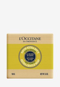 Savon L'Occitane en barre de forme carrée, emballage jaune clair avec une étiquette circulaire bleue, détails en blanc et noir, texture en relief, 100g.