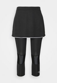 Svart idrottsshort med en slät textur och vit kant vid nederkanten, tillsammans med svarta leggings med glänsande accenter vid knäna.