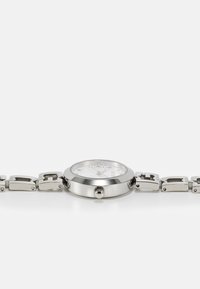 Zilveren roestvrijstalen horloge met een ronde wijzerplaat, witte gestructureerde wijzerplaat en een schakelarmbandontwerp. Bevat een kroon voor aanpassing.