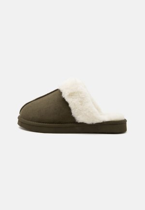 Chausson vert olive à enfiler avec une doublure polaire blanche douce et épaisse et une semelle plate, présenté de profil sur fond blanc.