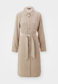 Beige kordflortklänning med långa ärmar, knäppning fram, två bröstfickor och ett tygbälte i midjan. Texturerad ribbad finish.