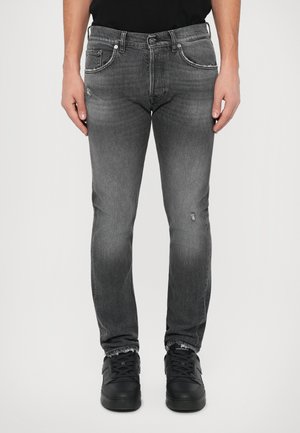 Szürke denim farmernadrág, slim fit szabással, elhalványult részekkel, enyhe kopásokkal, öt zsebből álló kialakítással és kontrasztos varrással, fekete sportcipővel párosítva.