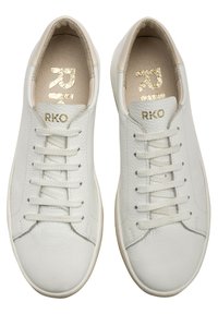 Białe skórzane sneakersy z zaokrąglonym noskiem, sześcioma oczkami, teksturowaną powierzchnią oraz złotym logo "RKO" na języku i wkładce.