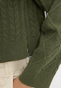 Pulover verde din tricot cu model împletit, cu margine și manșete cu tiv ribbed, având modele texturate și un finisaj moale, pufos. Potrivit pentru purtarea zilnică.