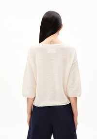 Ljusbeige stickad tröja med en avslappnad passform, vida ärmar och rundad halsringning. Har en liten etikett bak.