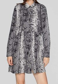 Abito a stampa serpente in bianco e nero con colletto, maniche lunghe e orlo svasato. Realizzato in tessuto morbido con un motivo testurizzato.