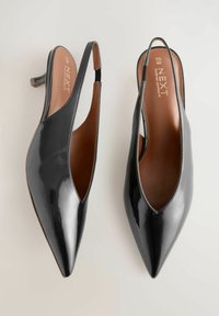 Musta lakattu nahkainen slingback-kengät, teräväkärkinen muotoilu, jossa on leikattu yksityiskohta, matala korko, kontrastivärinen vaaleanruskea sisäpohja ja hillitty brändäys.