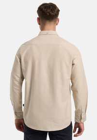 Camisa de manga larga beige de algodón con un cuello estándar, con puños abotonados y dobladillo recto. Textura suave, con detalles mínimos.