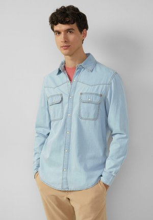 Lichtblauwe denim shirt met twee borstzakken, knoopsluiting aan de voorkant en een afgeronde zoom. Heeft contrasterende stiksels en een klassieke kraagontwerp.