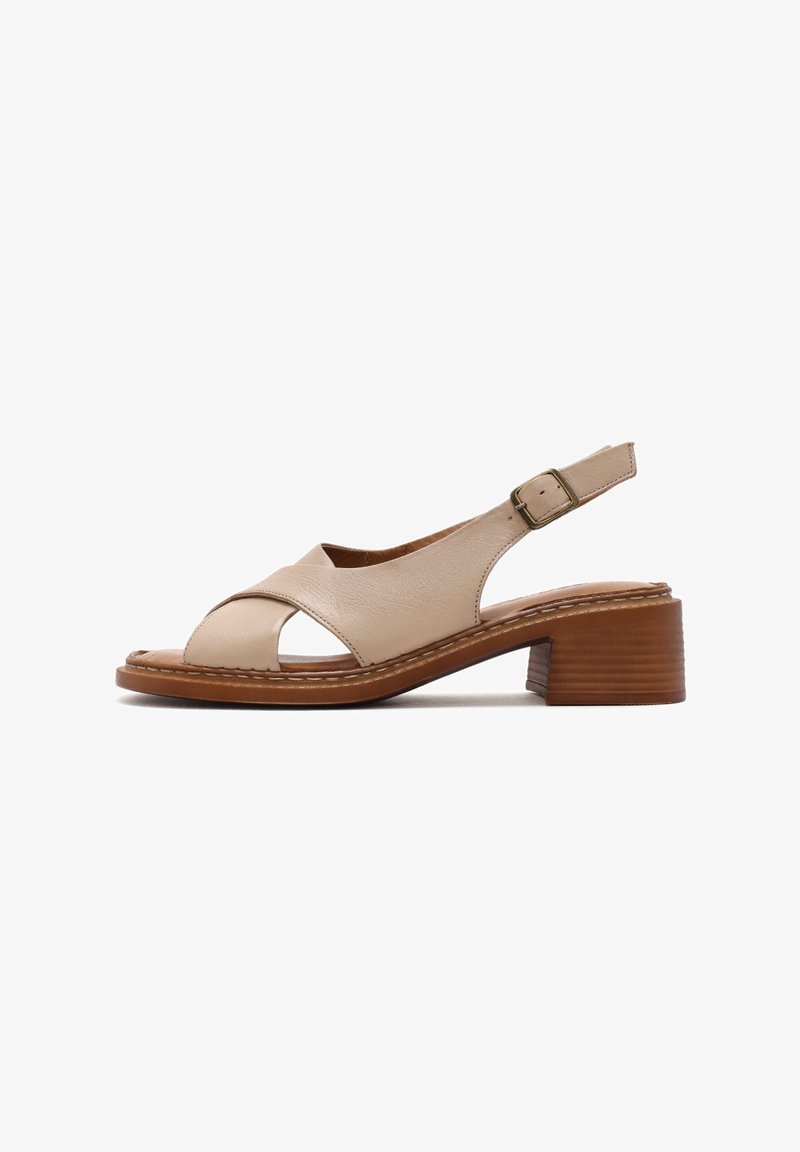 Sandale slingback en cuir beige à bout ouvert avec des brides croisées à l’avant, une boucle réglable, un petit talon bloc en bois empilé et une semelle cousue.