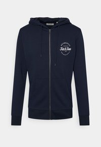 Sudadera con cremallera en color azul marino hecha de algodón, con un bolsillo frontal, capucha ajustable con cordón y un logotipo gráfico blanco en el pecho.
