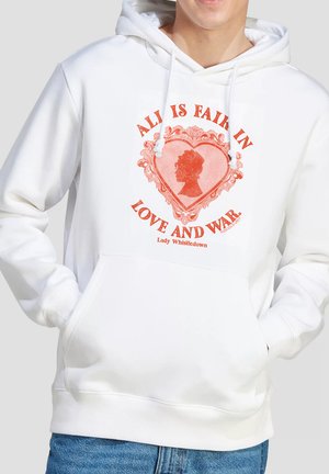 Person wearing white hoodie with red heart and silhouette design, text "ALL IS FAIR IN LOVE AND WAR" and "Lady Whistledown." Hands in pockets.
