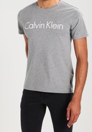Šedé tričko s krátkým rukávem a bílým logem "Calvin Klein" na přední straně, vyrobené z bavlněné směsi, s kulatým výstřihem a běžným střihem.