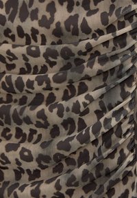 Tissu imprimé léopard présentant un mélange de tons beige et marron foncé, avec une texture froncée et une matière douce et transparente.