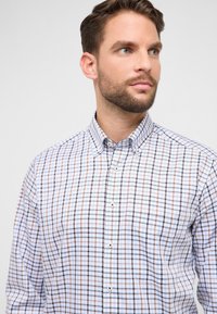 Geruit overhemd met blauwe, witte en bruine ruiten, vervaardigd uit geweven stof met een kraag en knoopdetails.