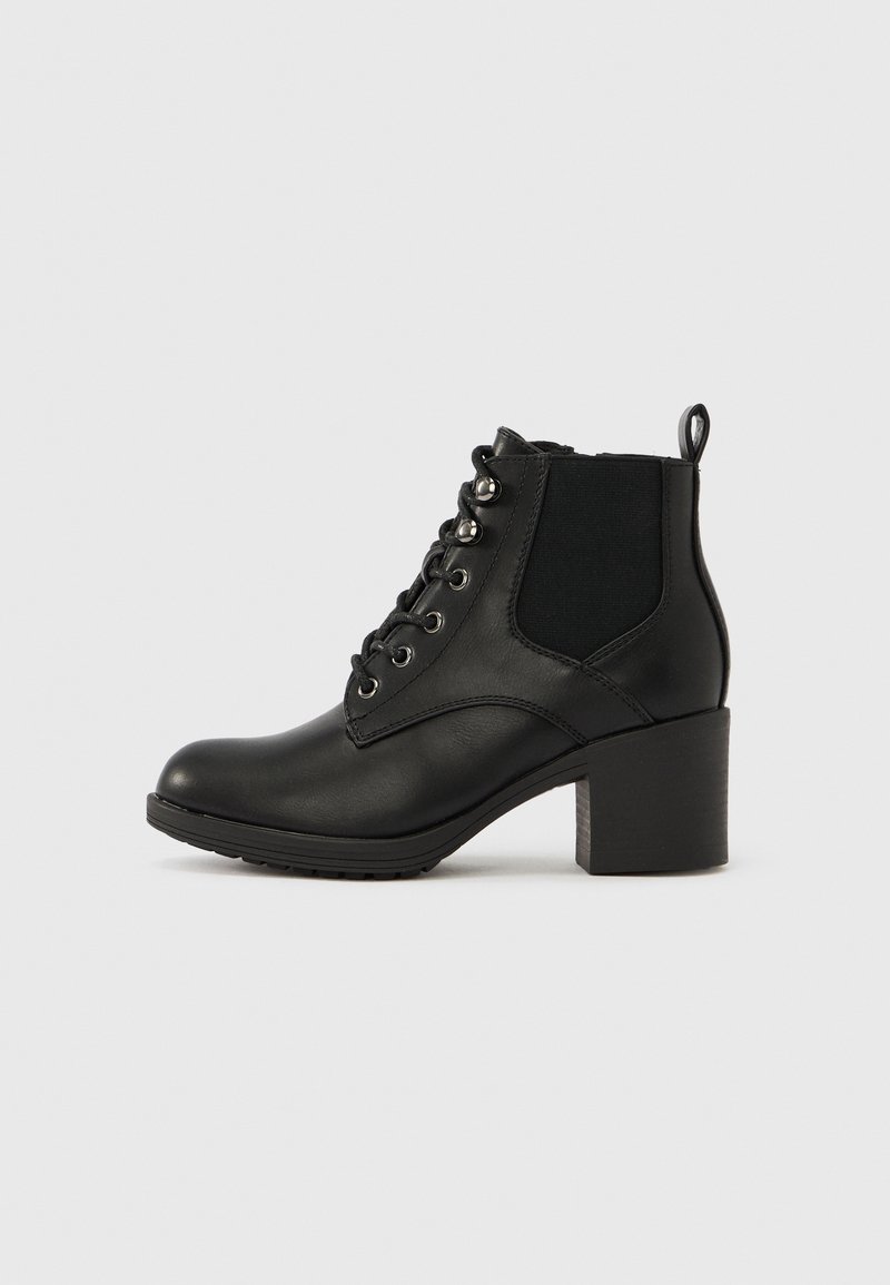 Bottine en cuir noir avec fermeture à lacets à l'avant, panneau élastique sur le côté, languette à l'arrière et talon bloc sur un fond clair uni.