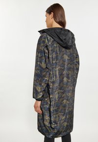 Lange, lichte regenjas in een donker camouflagepatroon. Heeft een zwarte capuchon en elastische manchetten voor een goede pasvorm. Gladde, glanzende stof.