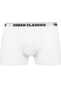 Vita bomullboxershorts med en snug fit, med ett svart elastiskt midjeband märkt "URBAN CLASSICS." Slät textur, enkel design.