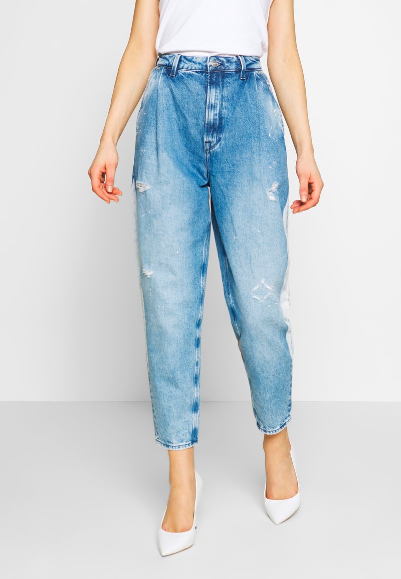 Jeans in denim azzurro chiaro con vita alta, vestibilità ampia e dettagli strappati. Presentano cuciture visibili e leggero scolorimento.