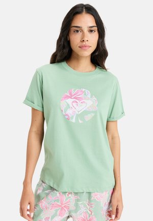 Light green cotton t-shirt with rolled sleeves and a circular floral graphic in pink, white, and pastel colors on the front.