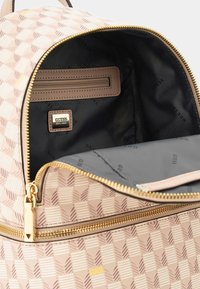 Zaino rosa con motivo e hardware dorato. L'interno presenta una fodera nera, una tasca con zip e un'etichetta con logo. Scomparto principale con zip.