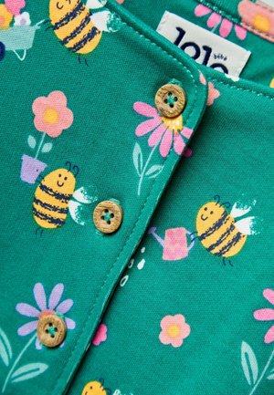 Grüner Baumwollstoff mit bunten Bienen- und Blumenmustern, Holzknöpfen und einer strukturierten Oberfläche.