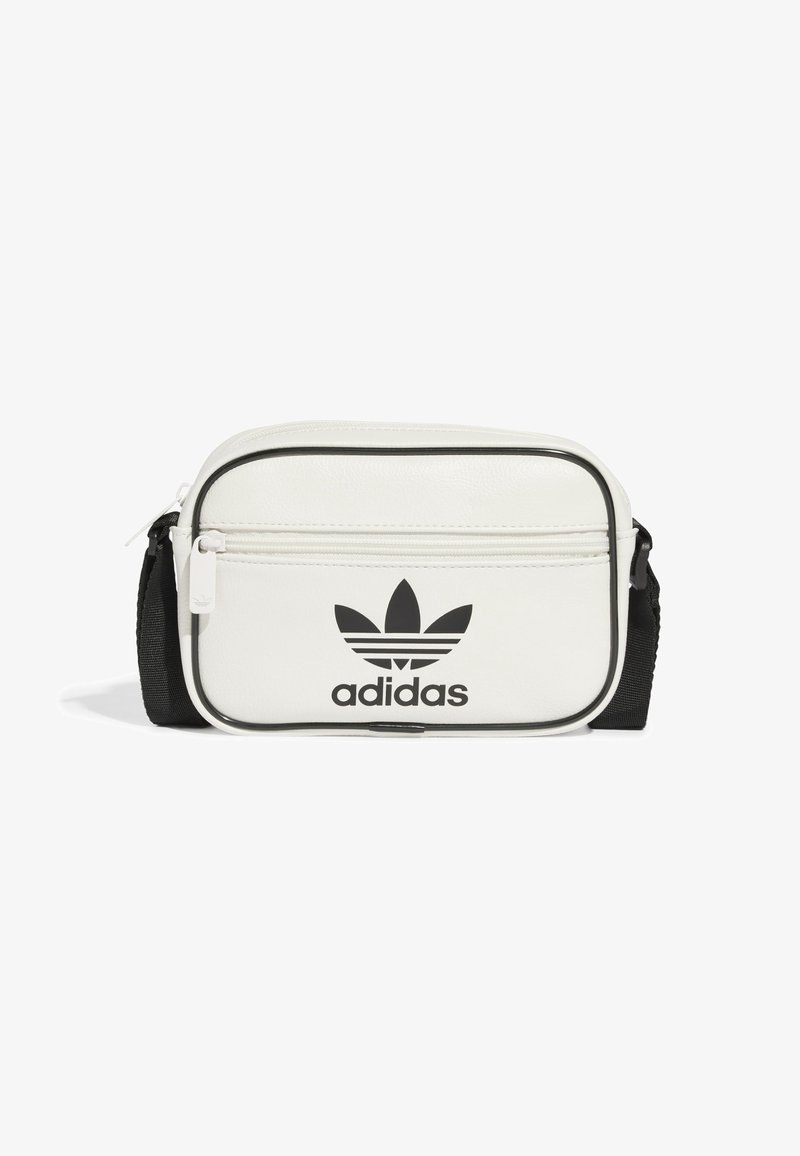Borsa a tracolla sintetica bianca con zip nera, tracolla nera e logo Adidas nero in evidenza sulla parte anteriore. Forma piccola e rettangolare.