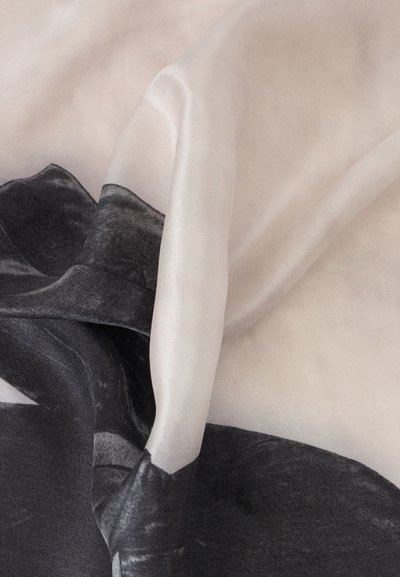 Tissu froissé avec un motif abstrait noir et blanc, montrant des plis et une texture dans un matériau doux et lisse.