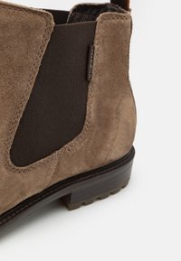 Braune Wildleder Chelsea-Boots mit elastischem Einsatz, kurzem Schaft und brauner Gummisohle. Mit einer gesteppten Naht und einem braunen strukturierten Akzent nahe der Ferse.