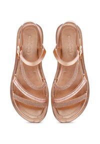 Rose gold sandals with a flat sole, featuring three sparkling straps and an ankle strap secured with a metal buckle. Smooth texture.